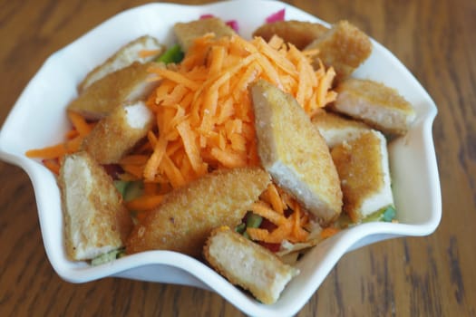 Tasty salad features crispy chicken pieces and grated carrots on top.