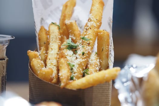 Fries topped with herbs and seasoning in a paper-lined box are ready to enjoy.
