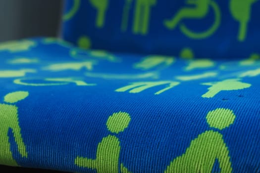 Colorful fabric features various accessibility symbols in green on blue.