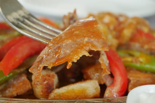 Tender grilled meat with colorful peppers being enjoyed during a meal.