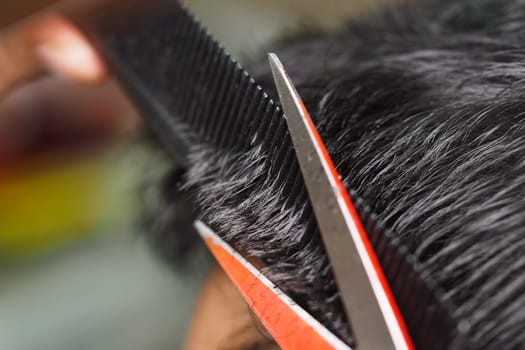 A stylist cuts hair with scissors while using a comb for precision.