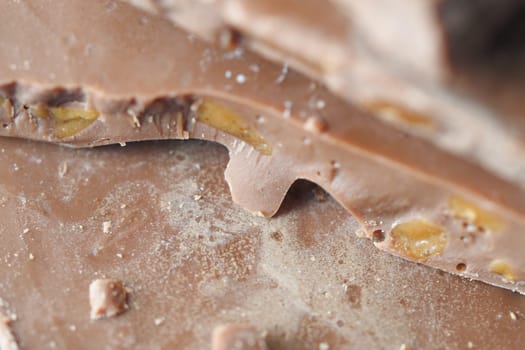 Close-up view of broken chocolate revealing caramel and nut pieces inside.