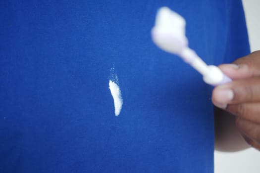A person is attempting to remove a toothpaste stain from a shirt.