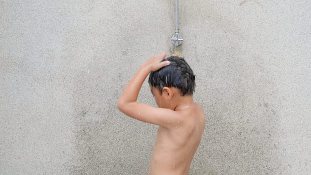 Asian child little boy taking shower at the swimming pool resort, Happy kid after swim he cleaning body refreshing and hyginic in tropical resort during family summer vacation