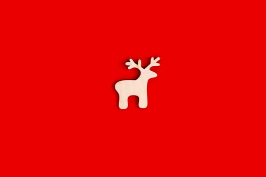 Deer figurine, flat, natural, unpainted wooden shape on a red background. Close up. Copy space. Mock up