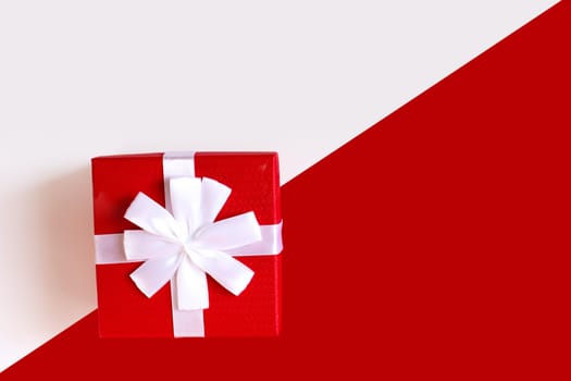Red and white diagonal paper texture, red gift box with white bow on it, background for template, horizontal. Top view. Mock up