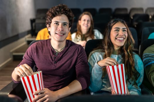 Happy couple enjoying a movie night at the cinema, sharing popcorn and smiles while immersed in the excitement of the big screen