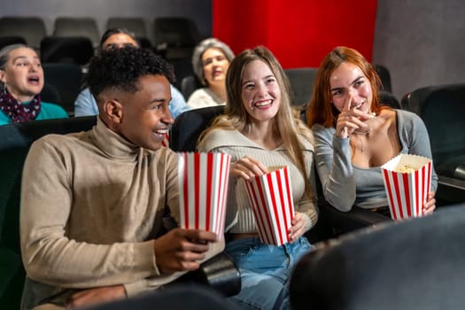 Young people enjoying a movie at the cinema, sharing laughter and popcorn, creating memorable moments together in a relaxed atmosphere