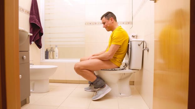 Man experiencing constipation, struggling on the toilet in a bathroom setting