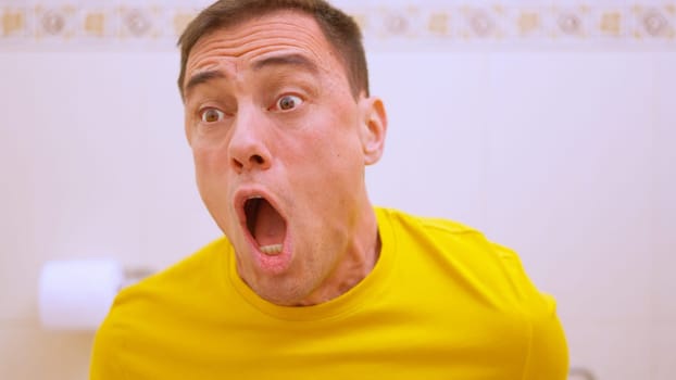 Man with surprised expression achieving his long awaited goal while sitting on the toilet