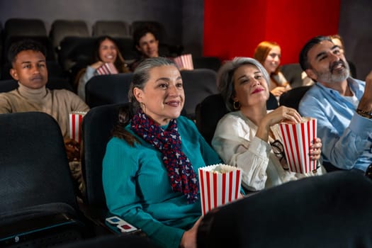 Diverse group of people enjoying a movie at the cinema, eating popcorn and wearing 3d glasses