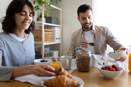 Happy couple having healthy breakfast at home.Woman grabbing croissant. Lifestyle concept.