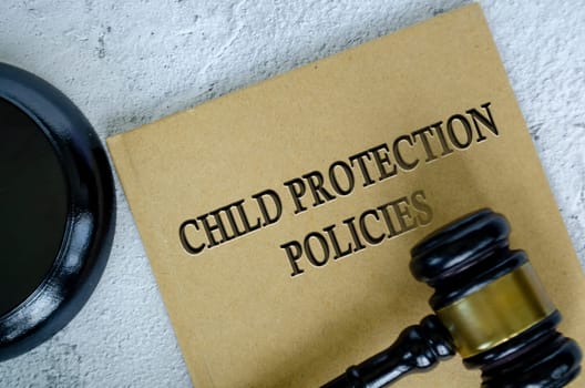 Top view of Child Protection Policies book with gavel on marble background.