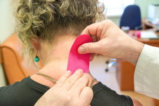Kinesiology taping. Kinesiology tape on patient neck. Injured trapezius muscles treatment of young male athlete.