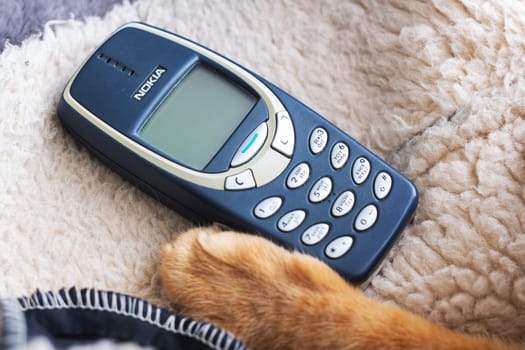 Belarus, Minsk - 11.01.2025: A Nokia phone is casually laying on a soft blanket next to a cats paw, creating a serene and cozy atmosphere in the scene