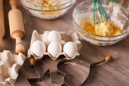 Children whisking flour and eggs in glass bowls while baking cookies together in a warm, rustic kitchen setting.