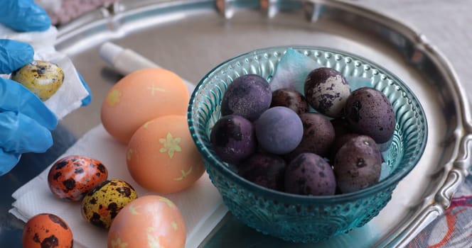 Colorful Easter eggs and unique quail eggs sit on a silver tray. The eggs, painted in vibrant hues, showcase intricate designs and invite festive joy.