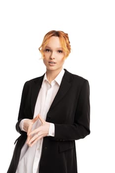 Self assured young female executive manager in formal suit standing against white background with hands together and looking at camera