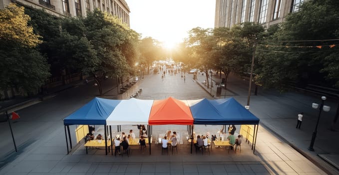 People dine al fresco under a striped canopy, enjoying a sunny city lunch.