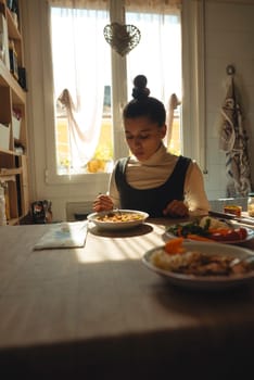 A woman is comfortably sitting at a table, savoring her delicious meal in a warm and inviting dining area
