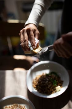 A hand spreads butter on a colorful dish, showcasing culinary creativity in a warm, inviting setting