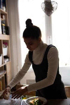 A woman carefully arranges a variety of delicious food on a plate in a bright, inviting kitchen atmosphere
