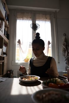 A woman is enjoying a wholesome and healthy meal at a beautifully sunlit kitchen dining table, filled with joy