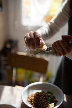 A person skillfully garnishes a nutritious and healthy dish with great care, emphasizing the art of home cooking