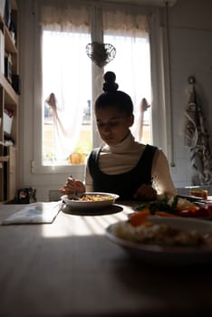 A woman delicately enjoys her meal within a cozy and warmly lit dining space, showcasing a moment of deep tranquility