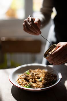 A dedicated person is carefully garnishing a delicious pasta dish with meticulous care within a cozy kitchen space
