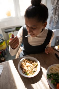 A young woman is savoring a delicious meal at a beautifully sunlit table, which is creating a cozy atmosphere