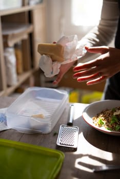A close-up of cheese preparation in a bright kitchen setting, emphasizing cooking and culinary arts.