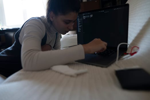 A focused individual deeply engaged in intricate tasks on a laptop, exemplifying a contemporary home office setup