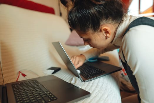 A woman is focused on her laptops, highlighting modern tech in a cozy setting that boosts her productivity