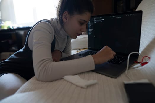 A devoted student, immersed in coding, is focused intently on a laptop in a cozy, creative environment