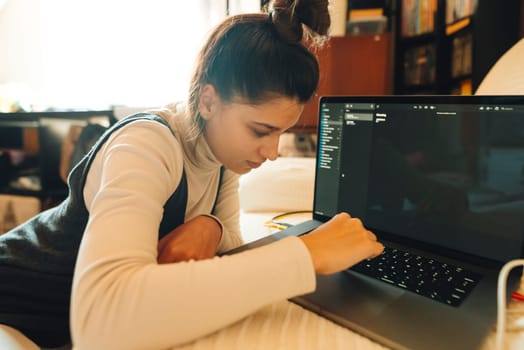 A young woman engaged in work on her laptop, showcasing productivity in a warm, inviting environment.