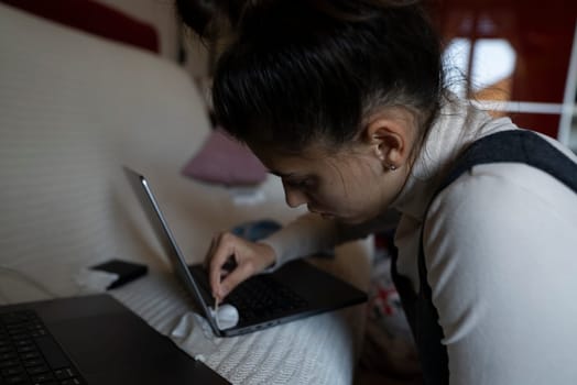 A focused individual is diligently engaged in working on their laptop while comfortably seated in their home