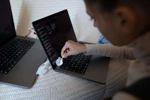 A person is cleaning a laptop keyboard, showing the importance of tech maintenance for better productivity