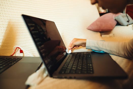 A user carefully wipes the surface of a laptop screen, showcasing a modern, stylish, and cozy workspace setup