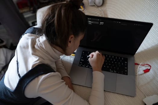A young person is intently typing away on a laptop, deeply immersed in their work within a cozy and comfortable space
