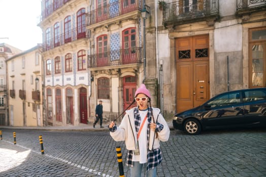 A very stylish individual confidently poses on a charming cobblestone street surrounded by colorful buildings