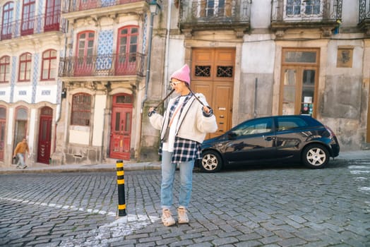A stylish young woman confidently poses in a picturesque street scene that features beautiful vintage architecture