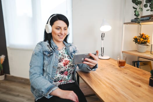 Smiling cute woman relaxing on couch listening to music on phone