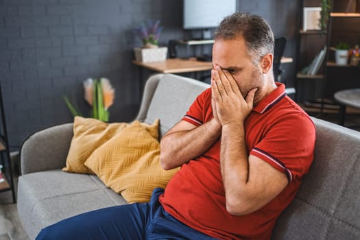 Man sitting alone at home looking sad and distraught.