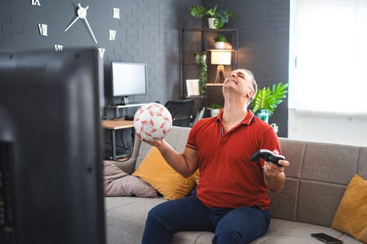 Middle age Caucasian man playing soccer video game at home.