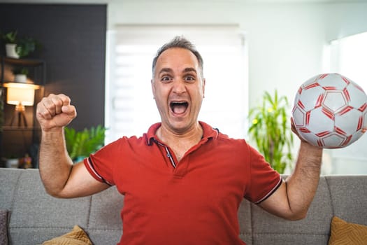 Excited middle aged man watching soccer game at home.
