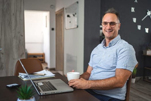 Middle aged Caucasian man working on laptop at home.