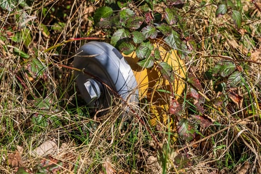 Close-up of a fire hydrant lying in the grass, highlighting environmental pollution from automotive waste
