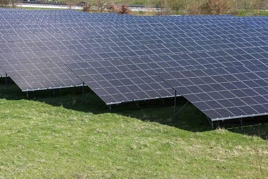 Rows of photovoltaic panels converting solar energy into electricity, providing a sustainable and clean energy source in a field near a highway