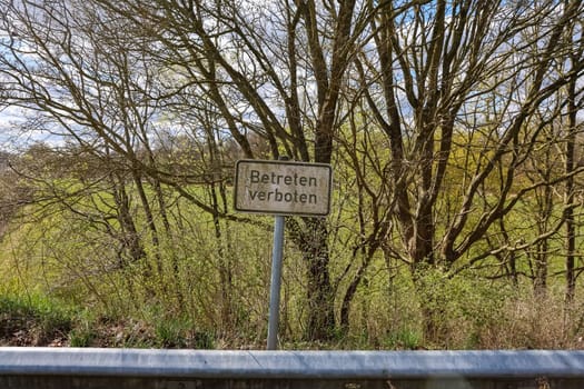 German no trespassing sign near a green field and trees, warning about restricted access and private property